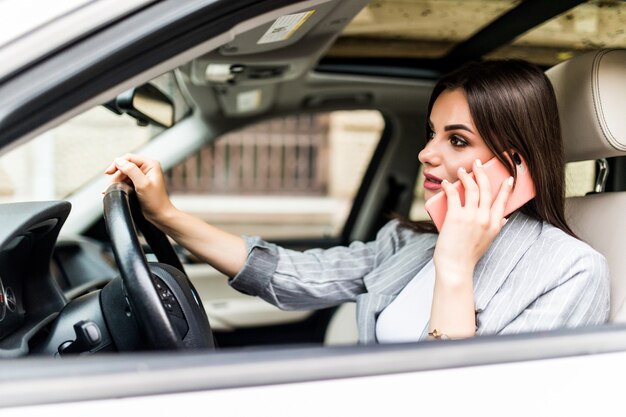 車を運転中に彼女の電話を使用して若いビジネスウーマン