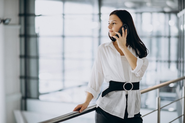 Молодая бизнес-леди используя телефон на офисе