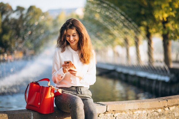 Young business woman using phone in park at lunch time