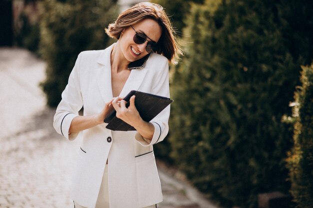 Young business woman in white suit talking on the phone outdoors