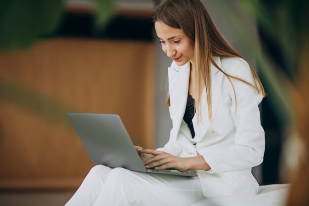 コンピューターに取り組んでいる白いスーツの若いビジネス女性