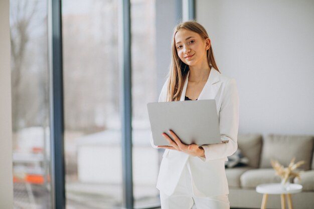 コンピューターに取り組んでいる白いスーツの若いビジネス女性