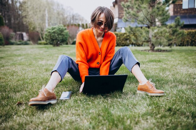Young business woman with laptop on the grass