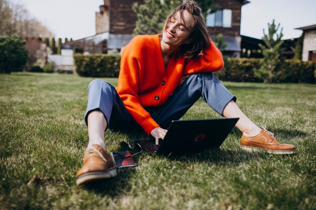 Young business woman with laptop on the grass