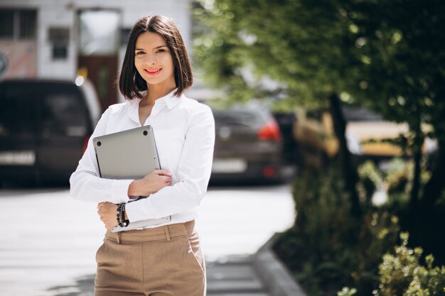 Young business woman with laptop outside the street