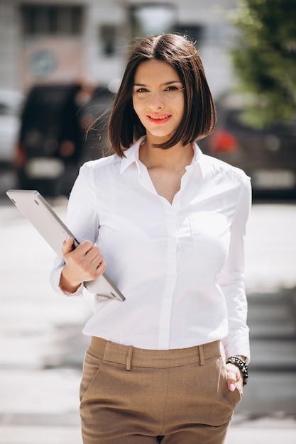 Free photo young business woman with laptop outside the street