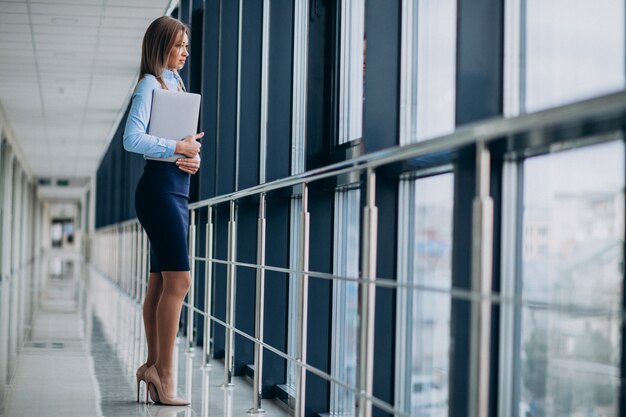 Young business woman with laptop standing in an office