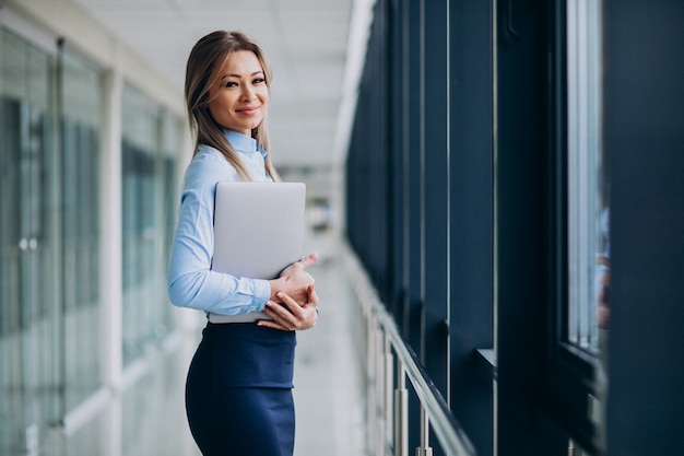 Young business woman with laptop standing in an office