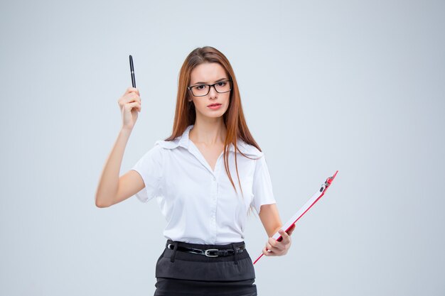 The young business woman with pen and tablet for notes on gray wall