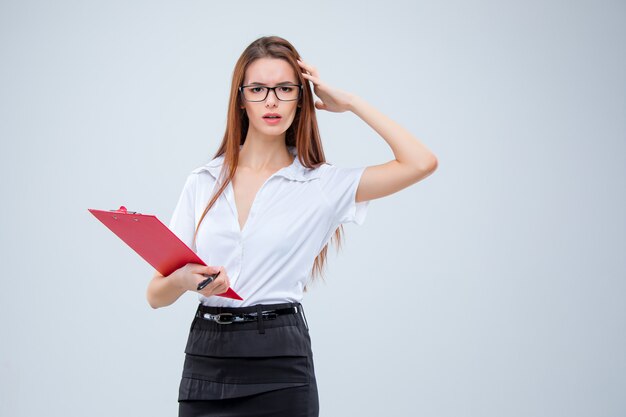 The young business woman with pen and tablet for notes on gray