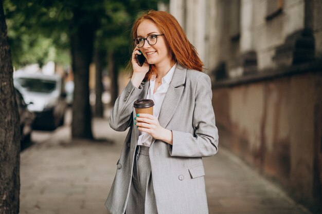 Молодая деловая женщина с рыжими волосами по телефону
