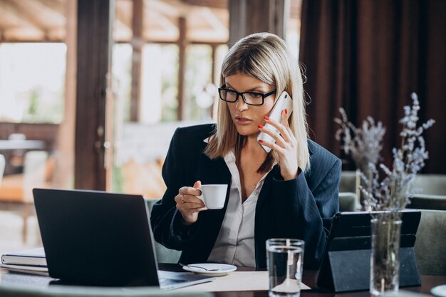 カフェ内のコンピューターに取り組んでいる若いビジネス女性