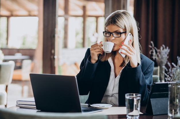 カフェ内のコンピューターに取り組んでいる若いビジネス女性