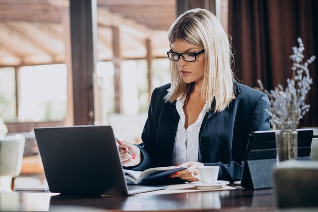 カフェ内のコンピューターに取り組んでいる若いビジネス女性