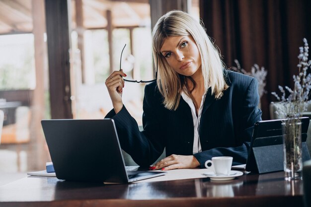 カフェ内のコンピューターに取り組んでいる若いビジネス女性