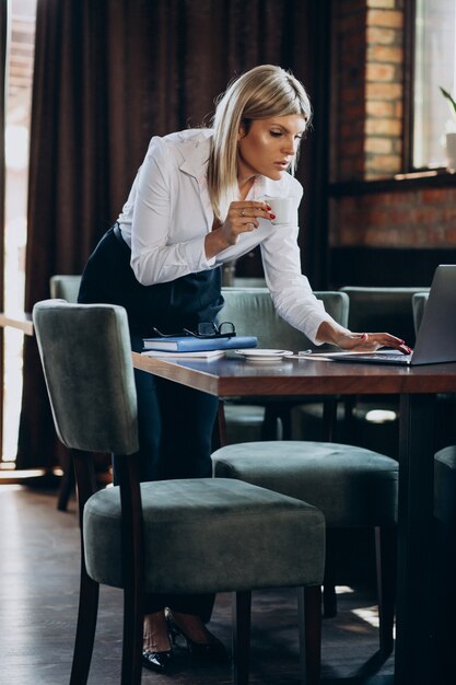 カフェ内のコンピューターに取り組んでいる若いビジネス女性