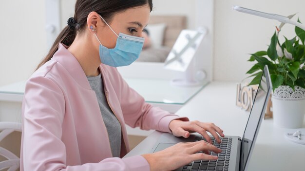 Young business woman working from home and wearing mask