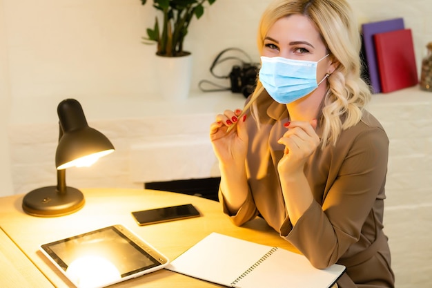 Free photo young business woman working from home wearing protective mask.