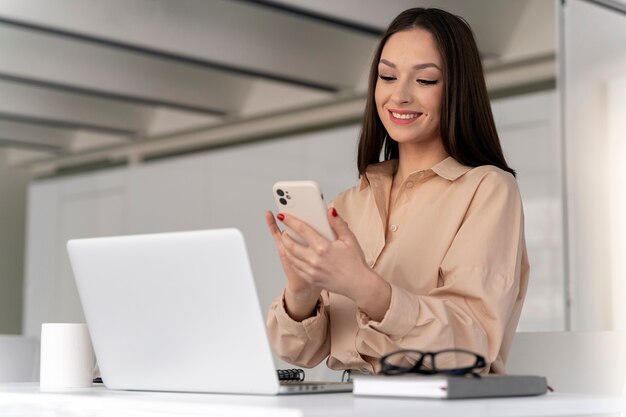 Young business woman working at her desk with smartphone