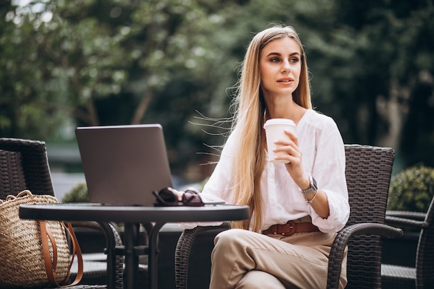 Young business woman working on laptop outside in a cafe