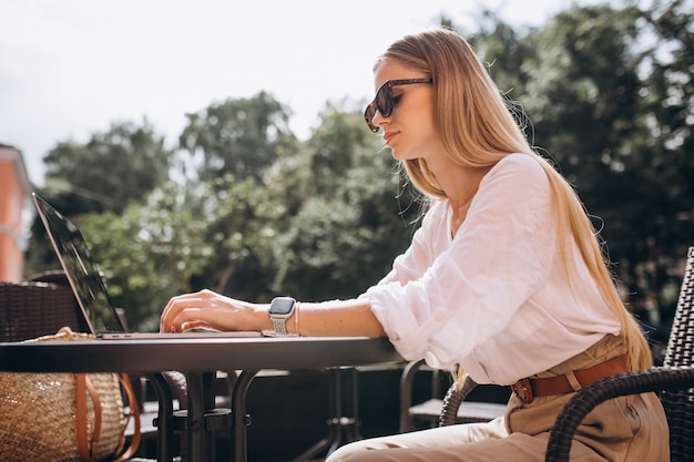 Giovane donna d'affari, lavorando su un computer portatile fuori in un caffè