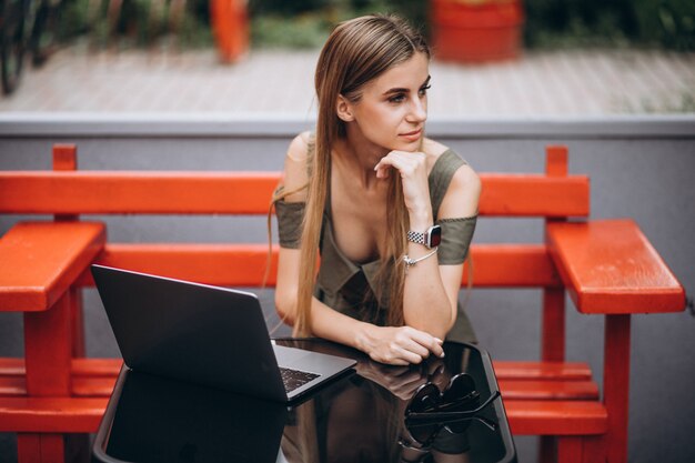 Young business woman working on laptop outside in a cafe