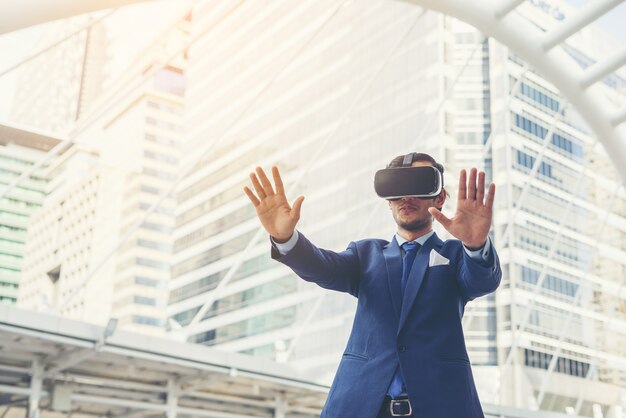 Young businessman in black suit wearing virtual reality goggles.