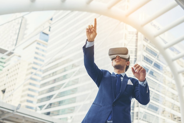 Young businessman in black suit wearing virtual reality goggles.