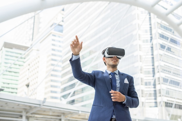 Young businessman in black suit wearing virtual reality goggles.