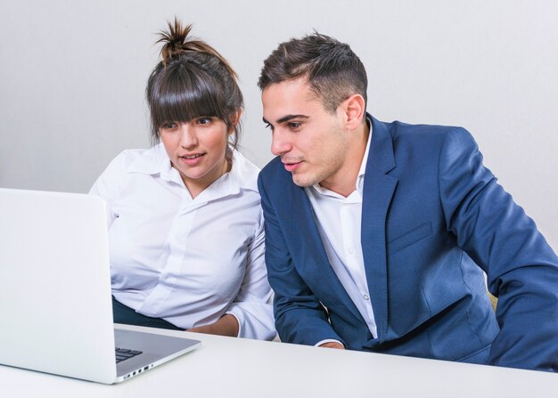Young businessman and businesswoman looking at laptop