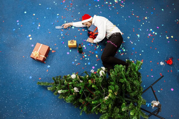 바닥에 자고 사무실에서 크리스마스를 축하하는 젊은 사업가.