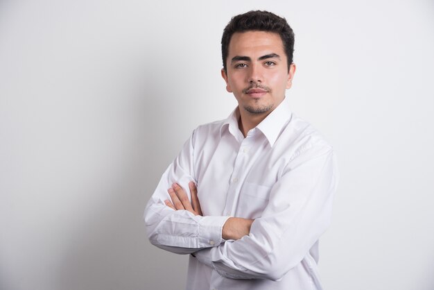 Young businessman crossing arms on white background.