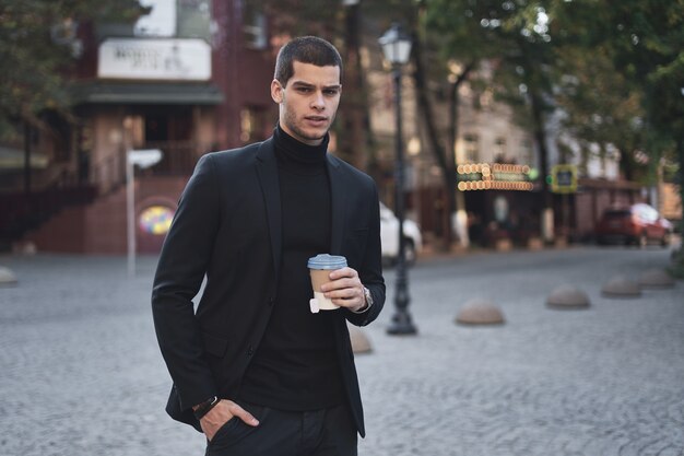 Young businessman going to the work with coffee