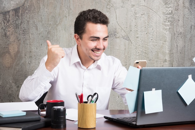 Young businessman got happy news at the office desk.