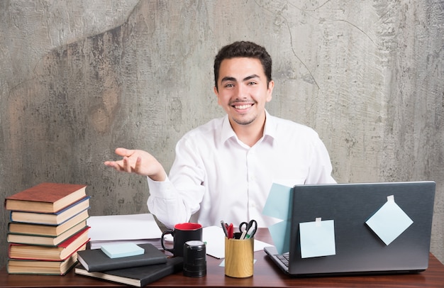 Young businessman happily looking at camera at the office desk.