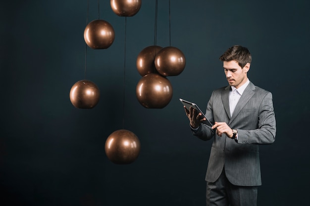 Free photo young businessman looking at digital tablet standing near the modern chandelier