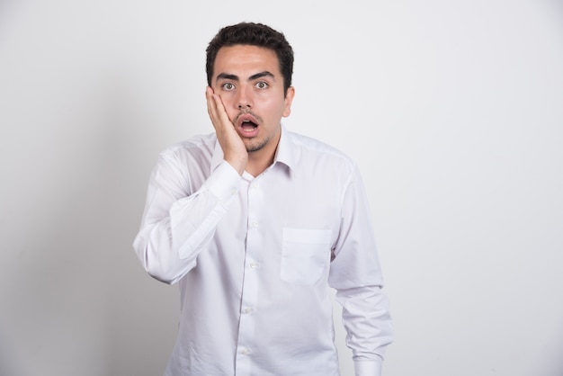 Young businessman looking shocked on white background.