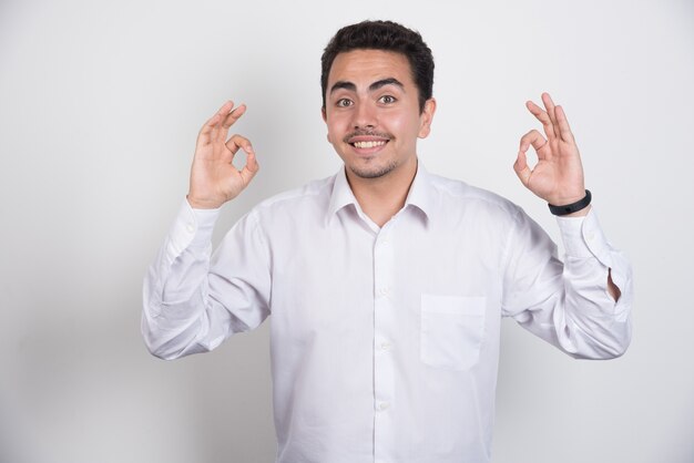 Young businessman making ok sign on white background.