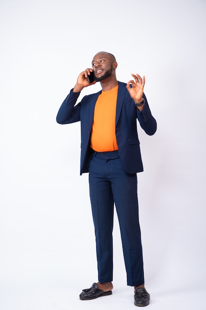 Young businessman making a phone call with ok hand gesture isolated on a white background