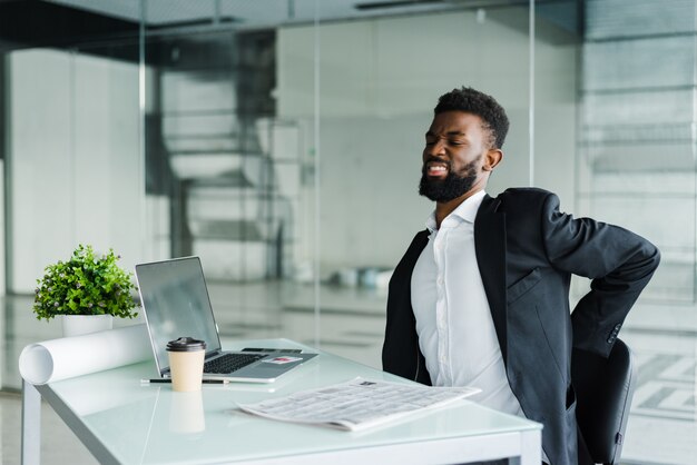 Young businessman in office at desk suffering from back pain in office