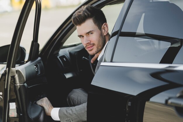 Young businessman opening the car door