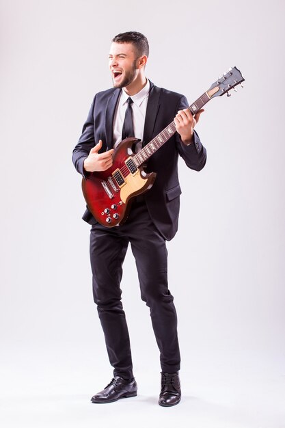 Young businessman playing guitar isolated on white wall