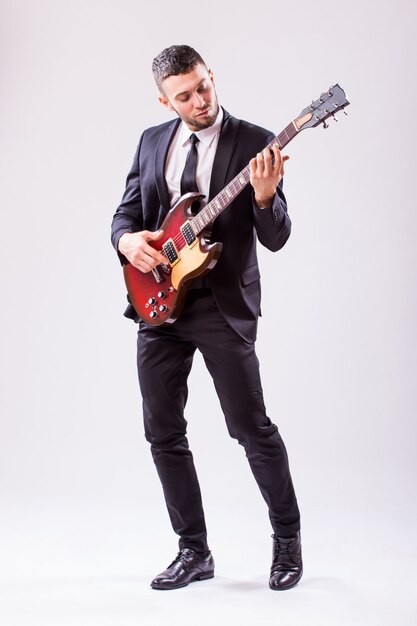 Young businessman playing guitar isolated on white wall