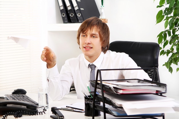 Free photo young businessman playing with paper airplane