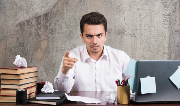 Young businessman pointing camera at the office desk.