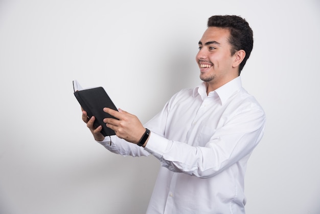 Young businessman reading notes on white background.