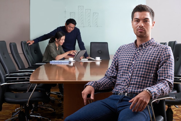 Young businessman seated in office chair looking at camera