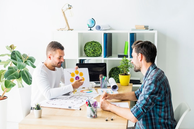 Free photo young businessman showing graph to his partner