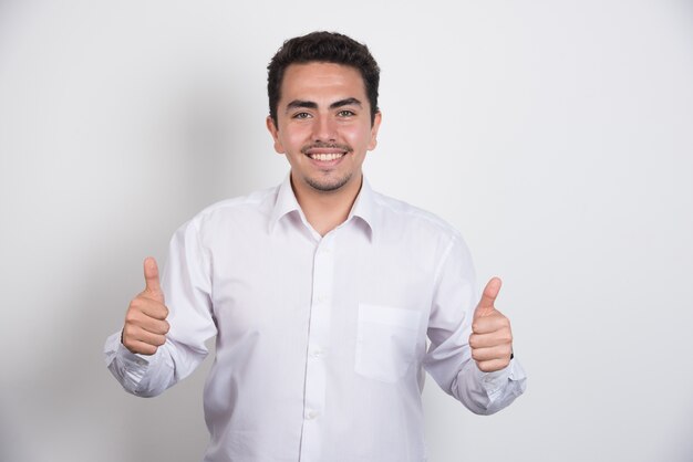 Young businessman showing thumbs up on white background.