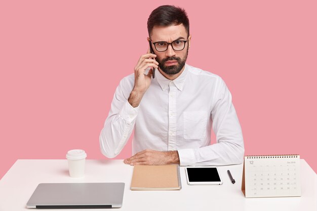 Young businessman sitting at desk with gadgets